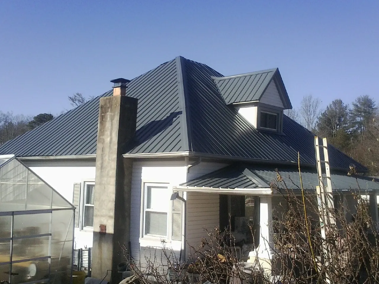 Dark blue standing seam metal roof on a white farmhouse with dormer — Slate & Tile Roof Repair by Roofing Brothers in West Mifflin