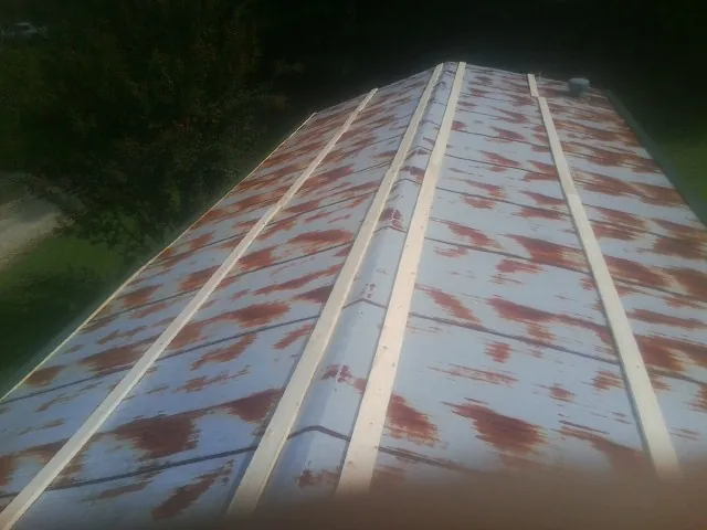 Rusted metal roof panels with new wood purlins before replacement in West Mifflin