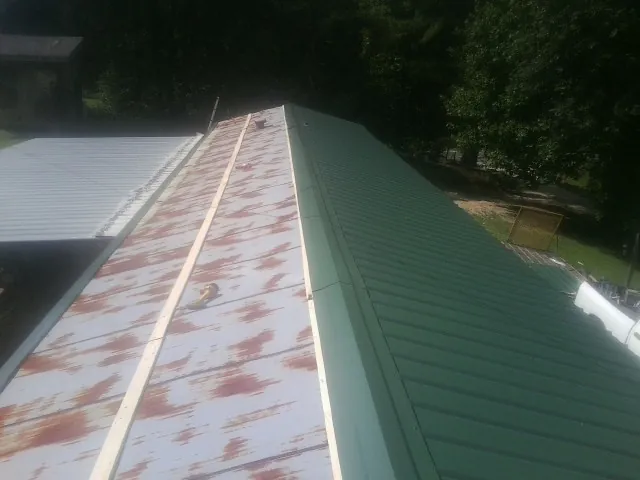 Old rusted panels beside newly installed green metal roofing — Wind Damage Roof Repair by Roofing Brothers in West Mifflin