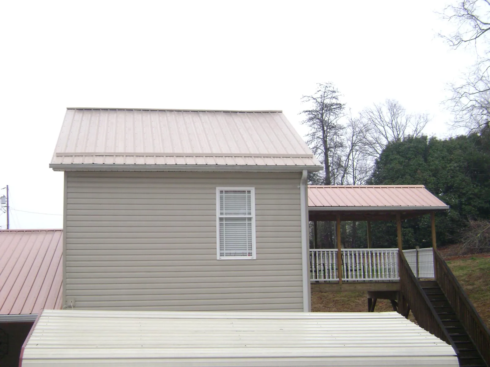 Tan metal roofs on a two story addition and attached porch, from a Roof Replacement job in West Mifflin