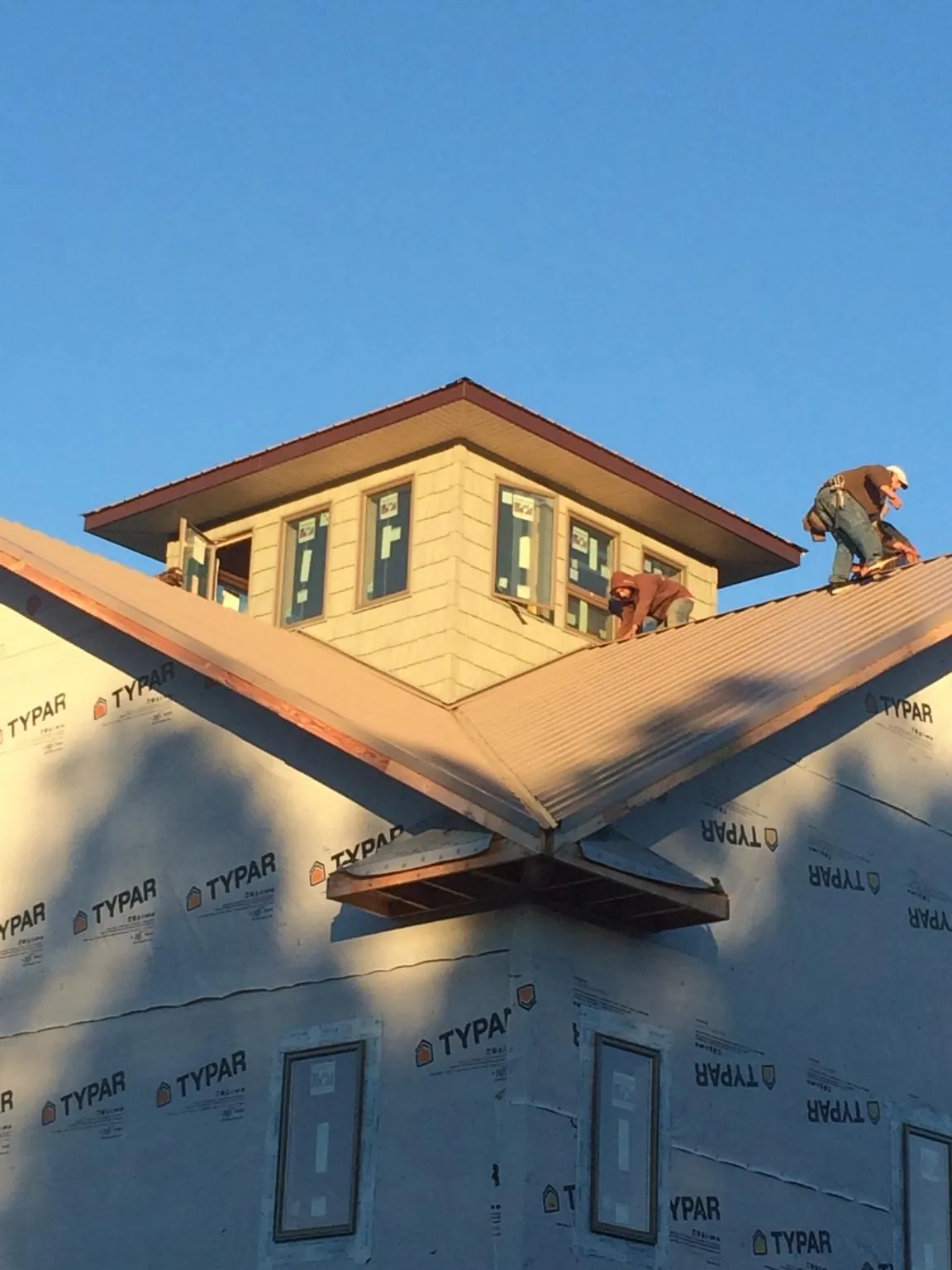 Roofers working around a rooftop cupola on a new metal roof at sunset — Roof Waterproofing in West Mifflin by Roofing Brothers